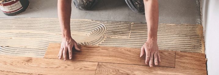 Ein Mann verlegt einen Fußboden aus Holz.
